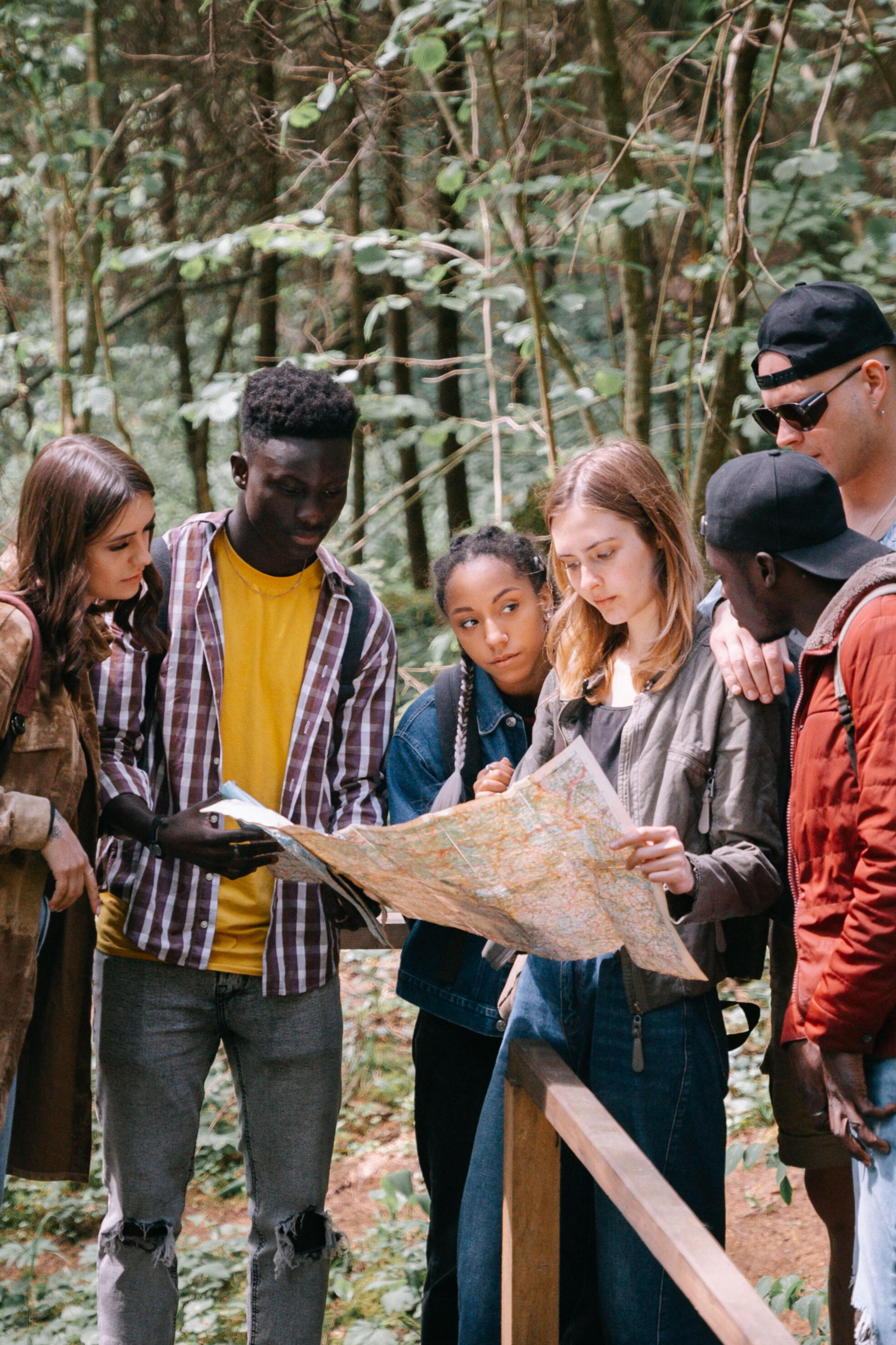 Trail users sharing local knowledge Six trail users studying a map together on a wooded trail.